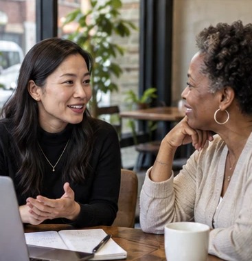 A dating coach talking with a client at a cafe table.